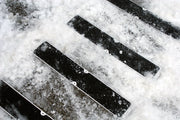 Set of black aluminum stair tread plates with non-slip grooves in snow, bolt holes